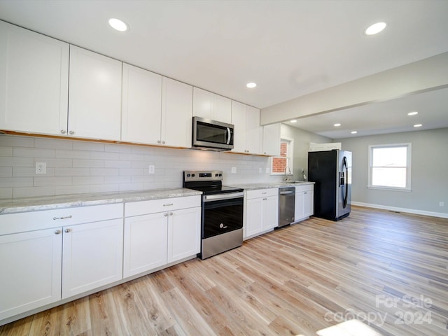 kitchen with decorative backsplash, appliances with stainless steel finishes, light wood-type flooring, light stone countertops, and white cabinets