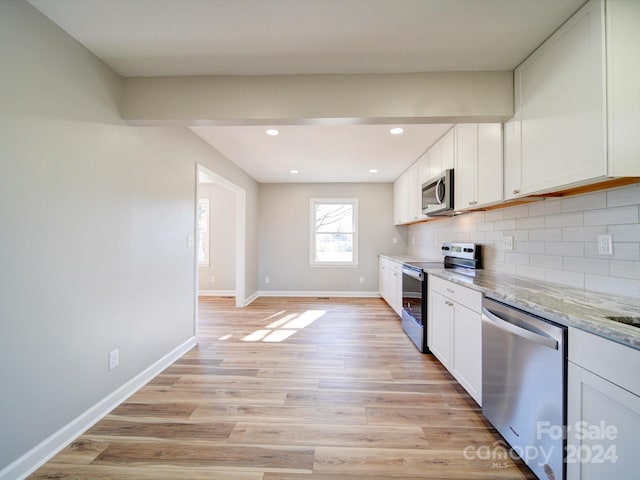 kitchen with white cabinets, light hardwood / wood-style floors, light stone counters, and appliances with stainless steel finishes