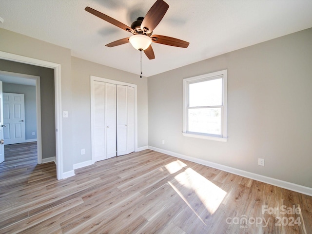 unfurnished bedroom with a textured ceiling, a closet, light hardwood / wood-style flooring, and ceiling fan