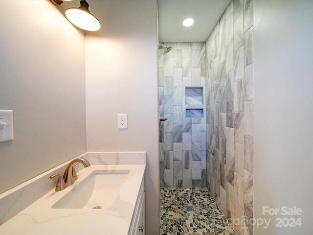 bathroom featuring tiled shower and vanity