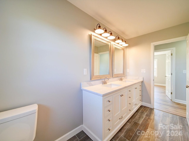 bathroom with wood-type flooring, vanity, and toilet