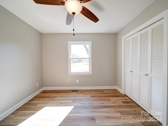 unfurnished bedroom featuring a closet, light hardwood / wood-style floors, and ceiling fan