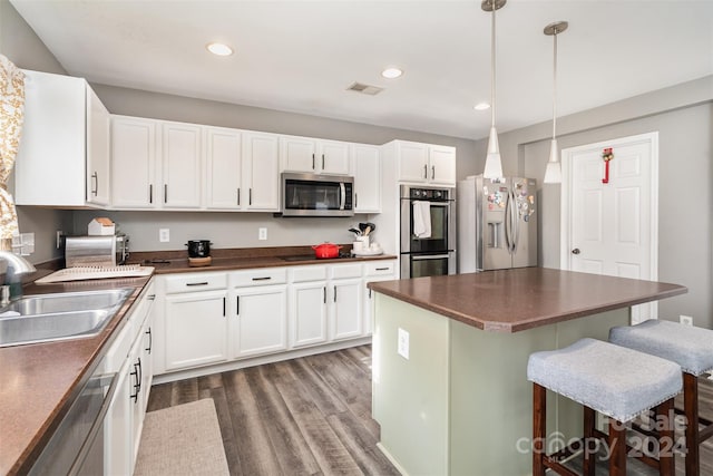 kitchen featuring pendant lighting, sink, appliances with stainless steel finishes, dark hardwood / wood-style flooring, and white cabinetry