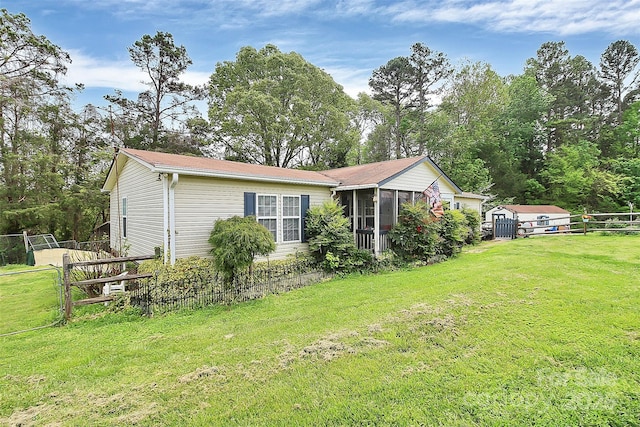 exterior space with a shed, fence, a lawn, and an outbuilding