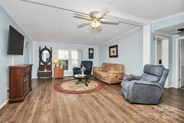 living room featuring baseboards, a ceiling fan, wood finished floors, crown molding, and a textured ceiling