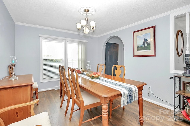 dining room featuring arched walkways, wood finished floors, a textured ceiling, and a chandelier