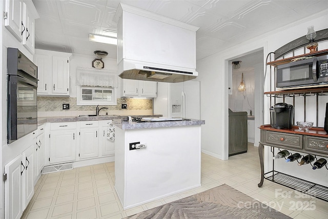 kitchen featuring light floors, light countertops, a sink, under cabinet range hood, and black appliances