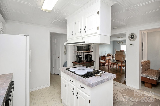 kitchen with an ornate ceiling, freestanding refrigerator, electric cooktop, and under cabinet range hood