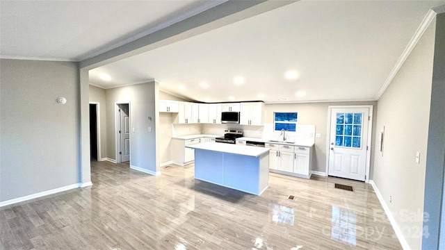 kitchen featuring appliances with stainless steel finishes, ornamental molding, a kitchen island, sink, and white cabinetry