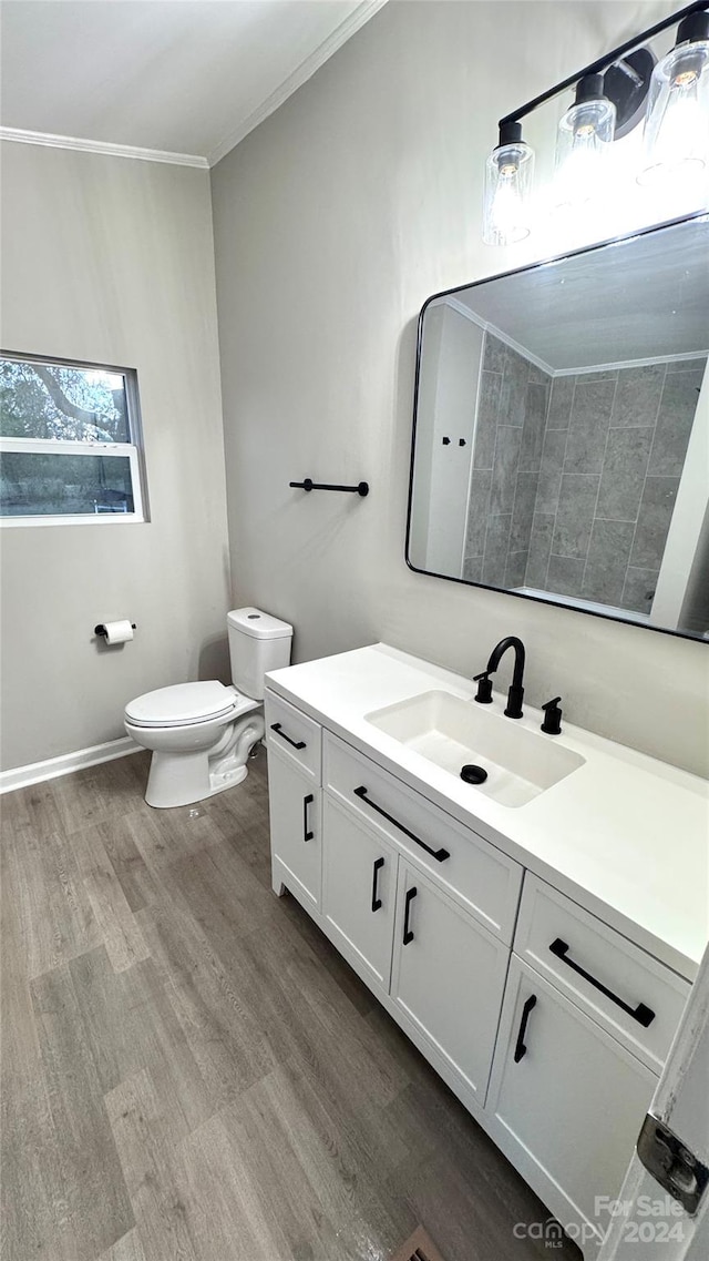 bathroom with hardwood / wood-style flooring, vanity, toilet, and ornamental molding