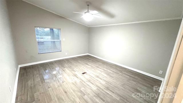 empty room featuring hardwood / wood-style flooring, vaulted ceiling, ceiling fan, and crown molding