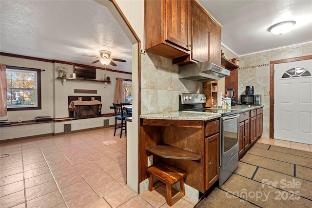 kitchen with a textured ceiling, tile walls, ceiling fan, stainless steel electric range, and ornamental molding