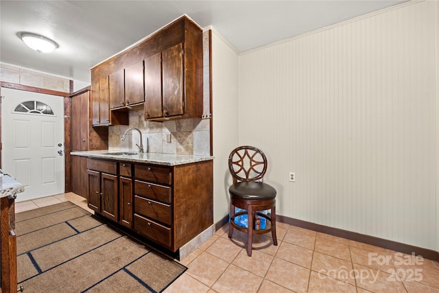 kitchen featuring sink, light tile patterned flooring, tasteful backsplash, dark brown cabinets, and light stone countertops