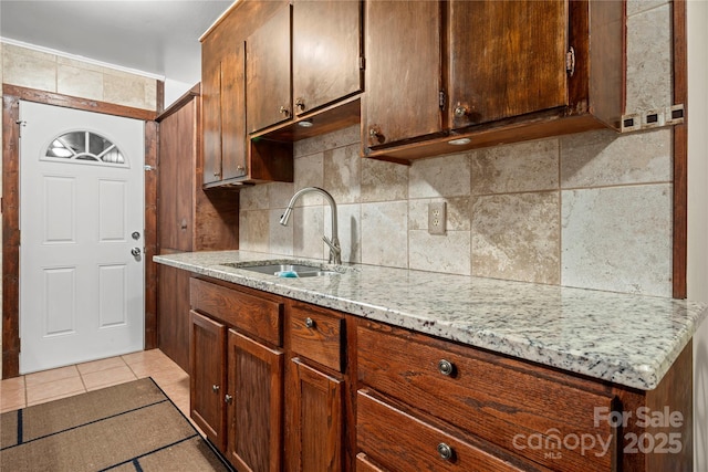 kitchen with sink, light tile patterned floors, tasteful backsplash, and light stone counters