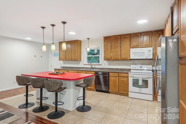 kitchen with appliances with stainless steel finishes, sink, a center island, hanging light fixtures, and a breakfast bar area