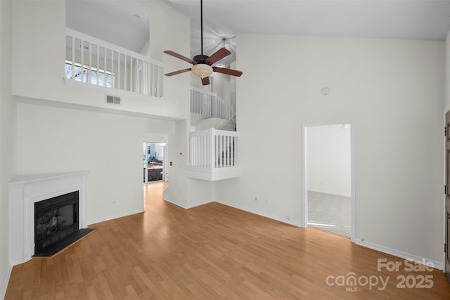 unfurnished living room with ceiling fan, high vaulted ceiling, and light hardwood / wood-style floors