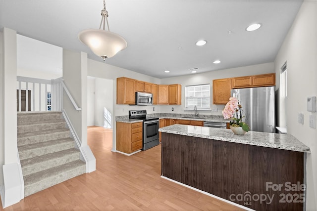 kitchen with sink, light hardwood / wood-style flooring, stainless steel appliances, light stone counters, and decorative light fixtures