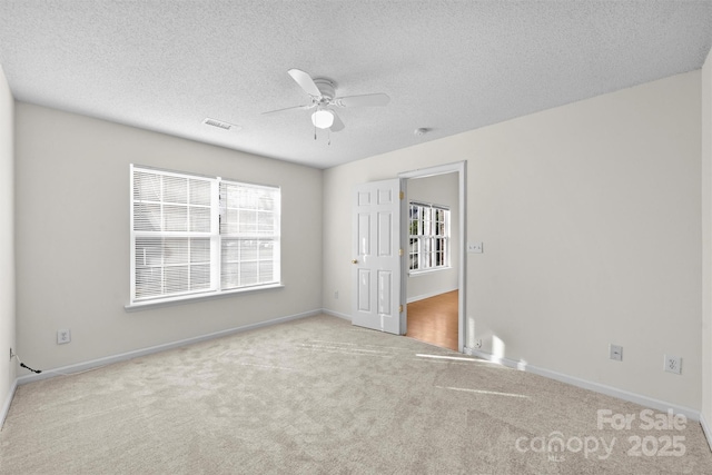 spare room with ceiling fan, light carpet, and a textured ceiling