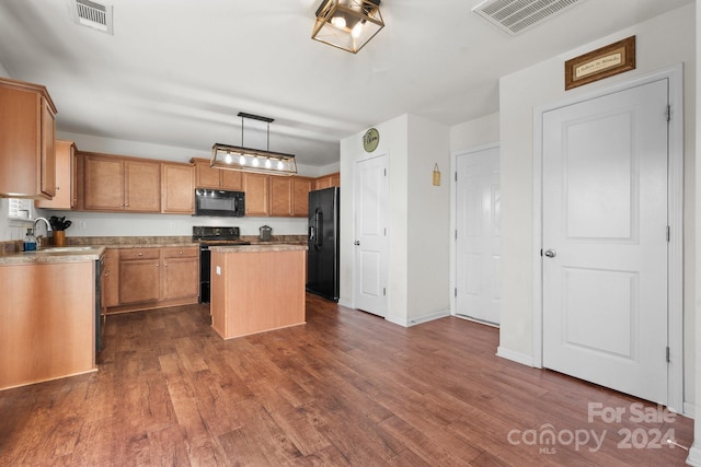 kitchen featuring a center island, sink, dark hardwood / wood-style flooring, pendant lighting, and black appliances