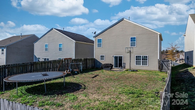 back of house with a lawn and a trampoline