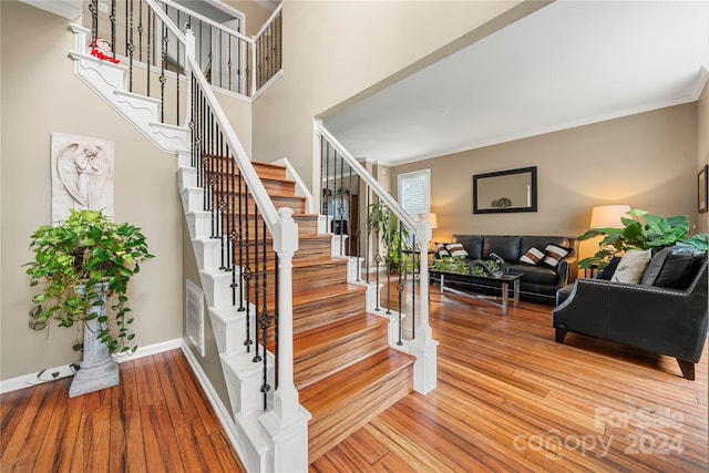 stairs featuring wood-type flooring and crown molding