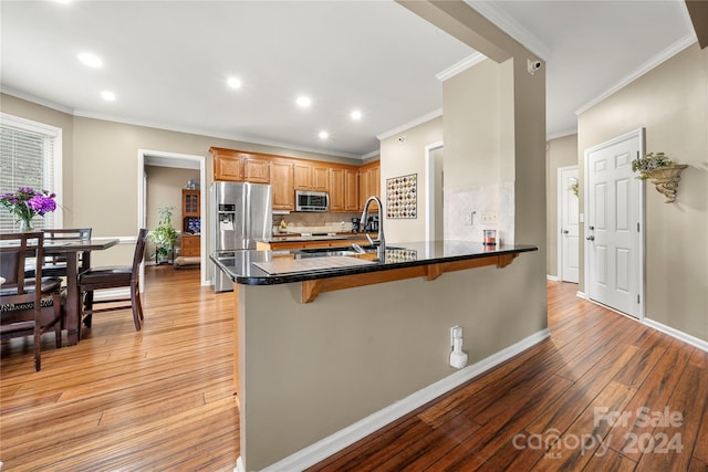 kitchen featuring kitchen peninsula, appliances with stainless steel finishes, a breakfast bar, and light wood-type flooring