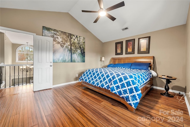 bedroom with ceiling fan with notable chandelier, hardwood / wood-style flooring, and vaulted ceiling