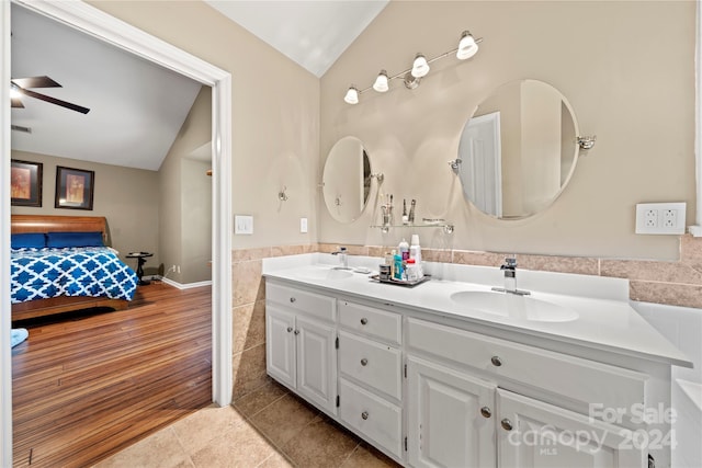 bathroom featuring vanity, ceiling fan, hardwood / wood-style flooring, tile walls, and lofted ceiling