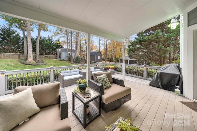 wooden deck featuring outdoor lounge area, grilling area, and a storage shed