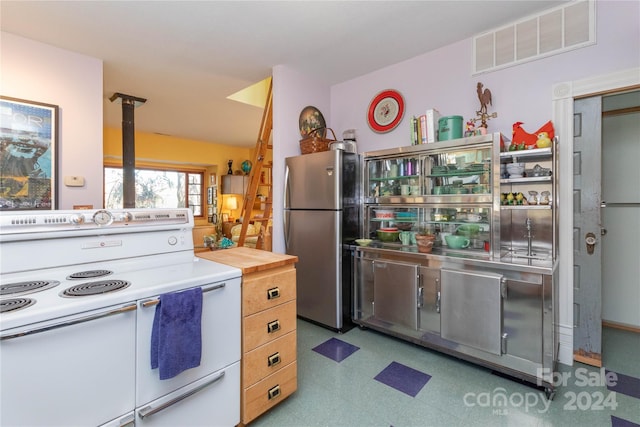 kitchen with white electric range oven, stainless steel refrigerator, and butcher block counters