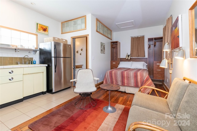 tiled bedroom featuring stainless steel fridge and sink