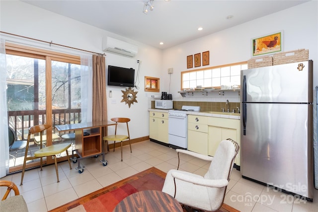 kitchen featuring white appliances, sink, tile counters, light tile patterned flooring, and a wall unit AC