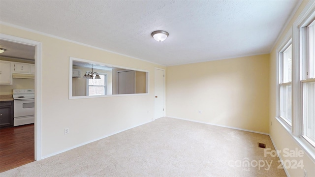 unfurnished room featuring carpet, a textured ceiling, a wall mounted air conditioner, and a chandelier