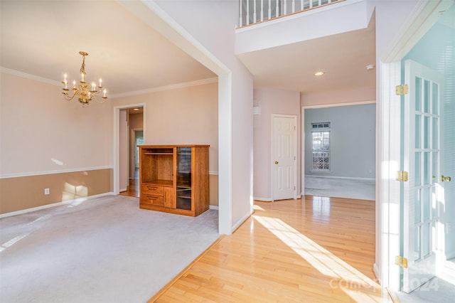 foyer featuring wood-type flooring, ornamental molding, and a notable chandelier