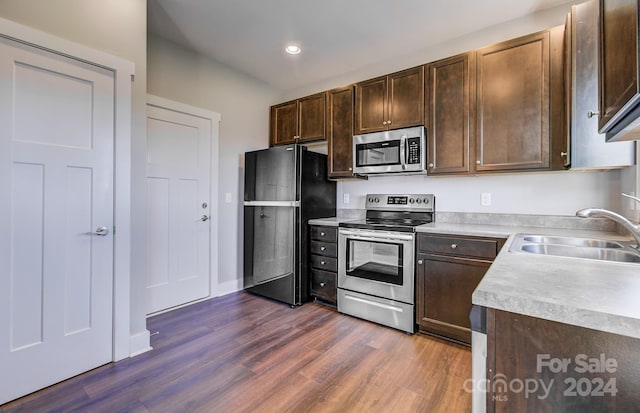 kitchen with sink, dark brown cabinets, dark hardwood / wood-style flooring, and stainless steel appliances