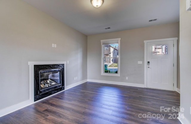 unfurnished living room featuring a high end fireplace and dark hardwood / wood-style floors