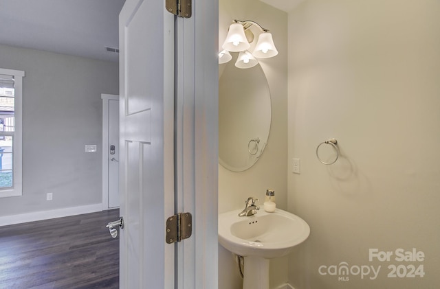 bathroom with hardwood / wood-style flooring, a notable chandelier, and sink