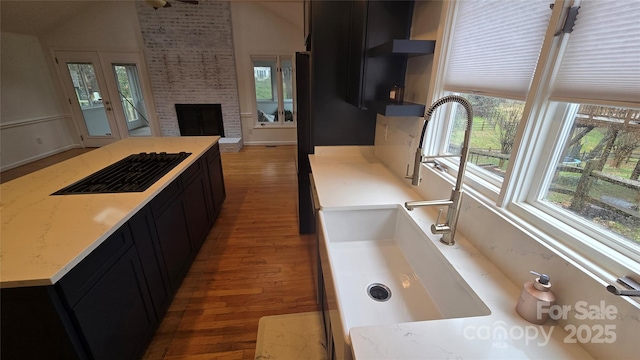 kitchen with wood finished floors, open floor plan, dark cabinets, and a fireplace