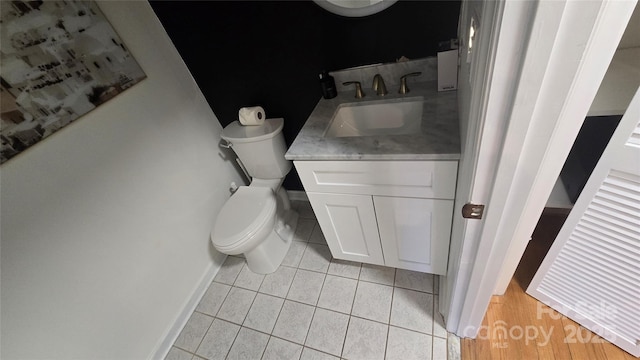 half bath with vanity, tile patterned floors, toilet, and baseboards