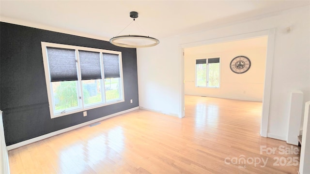 empty room featuring visible vents, light wood-style flooring, and baseboards