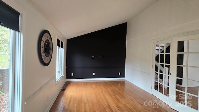 spare room with lofted ceiling, wood finished floors, and baseboards