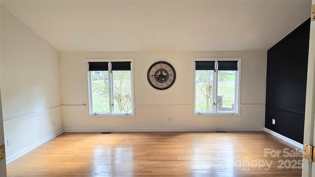 empty room featuring visible vents, baseboards, and wood finished floors