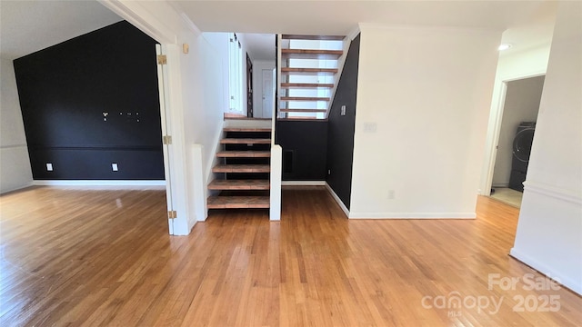 staircase with washer / clothes dryer, wood finished floors, and baseboards