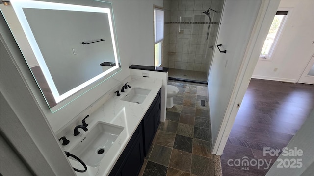 bathroom with a sink, tiled shower, toilet, and stone tile floors