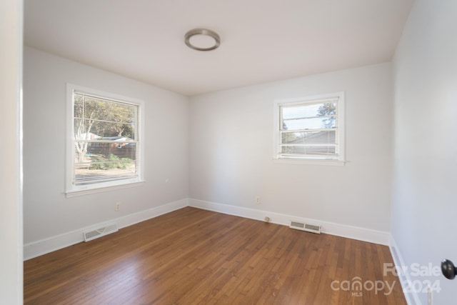 spare room featuring dark hardwood / wood-style flooring and a healthy amount of sunlight