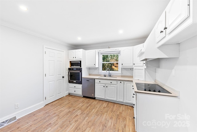 kitchen featuring white cabinetry, sink, black appliances, crown molding, and light wood-type flooring