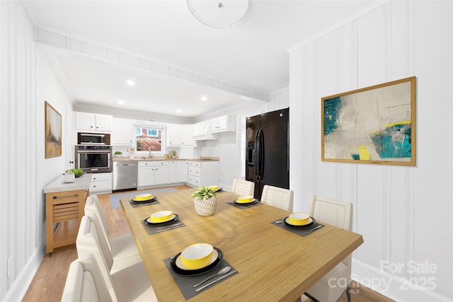 dining room featuring crown molding, sink, and light wood-type flooring