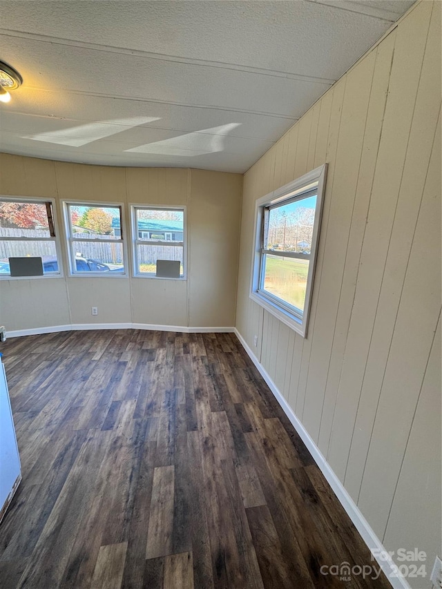 empty room with dark wood-type flooring and wood walls