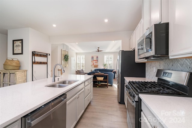 kitchen featuring backsplash, white cabinets, sink, appliances with stainless steel finishes, and light hardwood / wood-style floors