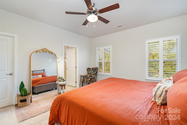 carpeted bedroom featuring multiple windows and ceiling fan